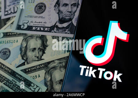 TikTok app Logo auf dem Bildschirm des Smartphones und US-Dollarnoten. Stockfoto
