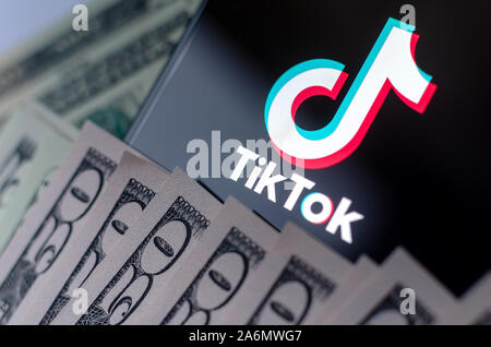 TikTok app Logo auf dem Bildschirm des Smartphones und US-Dollarnoten. Stockfoto