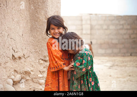 Zwei kleine afghanische Flüchtlinge kichern in Ihrem Haus in Karatschi, Pakistan Stockfoto