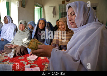 Vor einer Gruppe von Frauen, die eine VO (Dorf) treffen, ein Gruppenleiter zählt Afghani Notizen in Kucha teilnehmen - e-Abul Fazal Nachbarschaft in Kabul, der Hauptstadt Afghanistans. Stockfoto