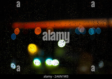 Wasser Tropfen am Fenster und Bokeh der Stadt in den Sonnenuntergang. Stockfoto