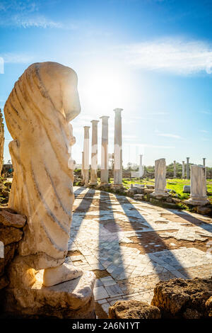 Marmorstatue unter der Sonne strahlen und antiken Säulen in Salamis, Griechische und Römische Ausgrabungsstätte, Famagusta, Nördlich Zypern Stockfoto