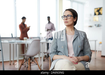 Porträt der moderne Geschäftsfrau weg schauen nachdenklich beim Sitzen auf Stuhl im Büro, Kopie Raum Stockfoto