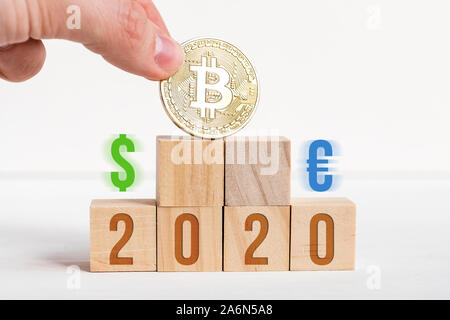 2020 Nummern auf holzwürfel auf weißem Hintergrund neben Bitcoin, Dollar, Euro. Der Begriff Prävalenz von cryptocurrency über das Übliche. Close Up. Stockfoto