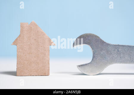 Abstrakte Pappe Haus neben einem Schraubenschlüssel. Immobilien Reparatur Konzept. Close Up. Stockfoto