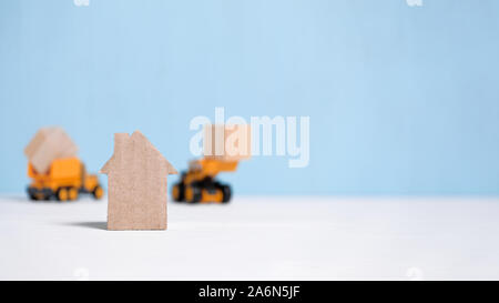 Abstrakte Pappe Haus neben Baumaschinen. Das Konzept der Baubeginn. Close Up. Kopieren Sie Platz. Stockfoto