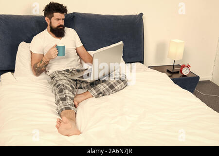 Schnell am Morgen unterhalten. Eine Pause. Zu viel Arbeit. All seine Energie zu arbeiten. Geschäftsmann mit Computer. bärtiger Mann Arbeiten am Laptop. Mann im Schlafzimmer Kaffee trinken. Energie und Müdigkeit. Stockfoto