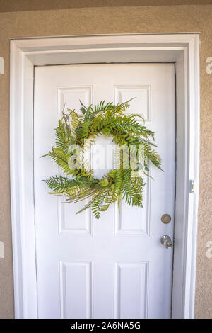Home entrance with close up view of a wreath hanging on the white front door Stockfoto