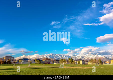 Grüne Sportplätze mit schneebedeckten Berge im Hintergrund Stockfoto