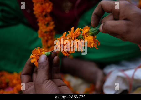 Kathmandu, Nepal. 27 Okt, 2019. Eine Nepalesische street Hersteller macht Ringelblume Blumengirlanden während Tihar Festival in Kathmandu, Nepal am Montag, 27. Oktober 2019. (Foto durch Rojan Shrestha/Pacific Press) Quelle: Pacific Press Agency/Alamy leben Nachrichten Stockfoto