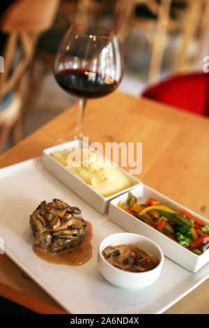 Rindfleisch mit Pilzsauce, Vorspeisen- und Rotwein auf dem Tisch im Restaurant Stockfoto