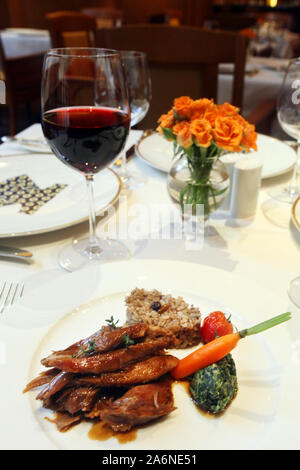 Fleisch mit Gemüse, Reis und Rotwein auf dem Tisch im Restaurant Stockfoto