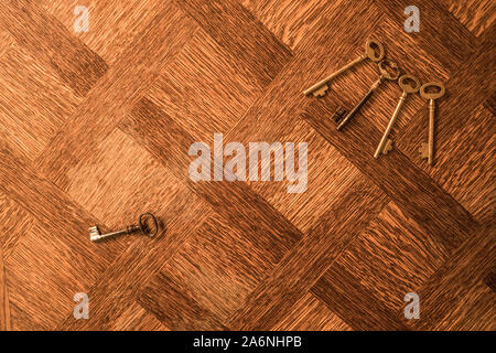 Paar Tasten an jeden anderen suchen, auf Schlüssel ist mit einem einzelnen, auf Holztisch, Ansicht von oben, flach. Stockfoto