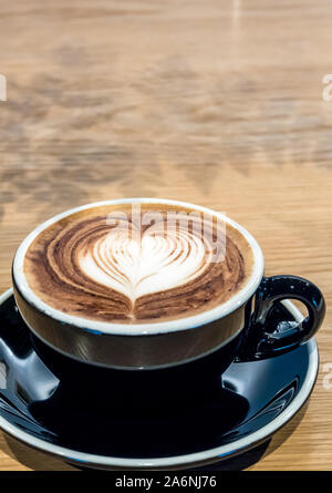 Kaffee in schwarzer Schale auf Holztisch Stockfoto