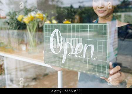 Close-up-Bild der weiblichen Blüte shop besitzer hängen"-Schild auf Glas Tür Stockfoto