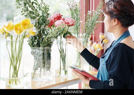 Professionelle Floristen den Bestellstatus auf Tablet Computer auswählen und Blumen in Vasen auf shop Fensterbank Stockfoto