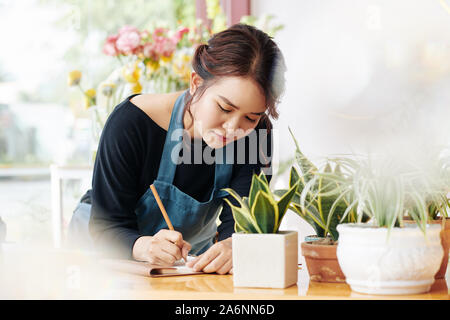 Jungen Asiatischen florist Schreiben Liste der Dinge, die sie braucht, um heute zu tun Stockfoto