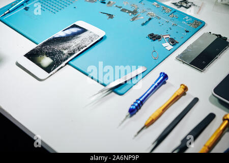 Smartphone mit zertrümmert, Werkzeuge und Details auf dem Schreibtisch der Handwerker Stockfoto