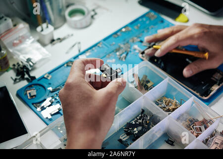 Tablet PC-Hauptplatine in der Hand der Handwerker auf der Suche nach genauso detailliert in Kunststoffbox Stockfoto