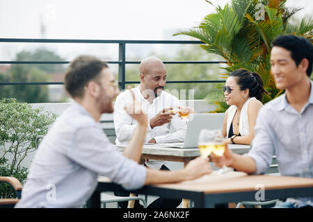 Business Paar an Café im Freien sitzen und Toasten mit Champagner Gläser nach dem Abkommen Stockfoto