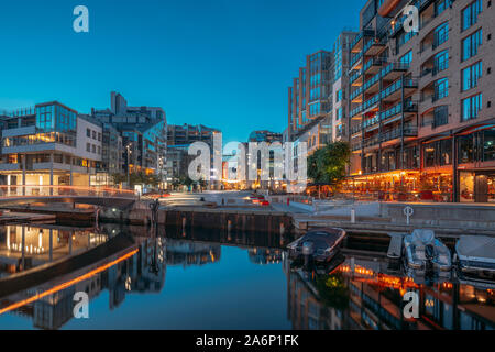 Oslo, Norwegen - 24. Juni 2019: Night View Embankment und Wohngebiet mehrstöckige Häuser im Viertel Aker Brygge. Sommerabend. Wohngebiet Refl Stockfoto