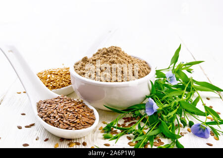Leinsamen Mehl in eine Schüssel geben, weiße und braune Bettwäsche Samen in zwei Löffel und am Tisch, Blätter und Blüten von Flachs auf Holzbrett Hintergrund Stockfoto