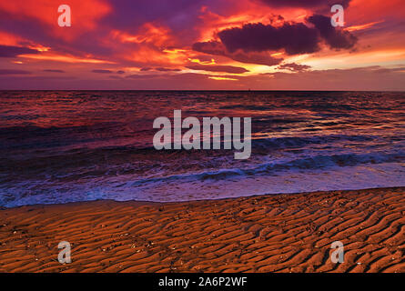 Schöne lebendige dramatische Wolkenhimmel winter Sonnenuntergang auf einem sandigen Strand texturiert. Stockfoto