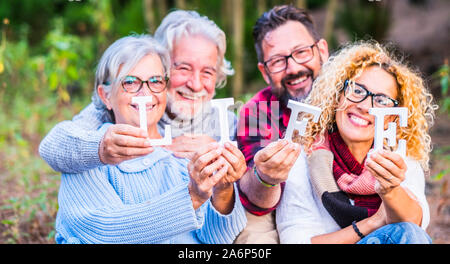 Vier lächelnde Menschen halten das Wort Leben in den Händen - zwei Generationen von Vater und Sohn Stockfoto