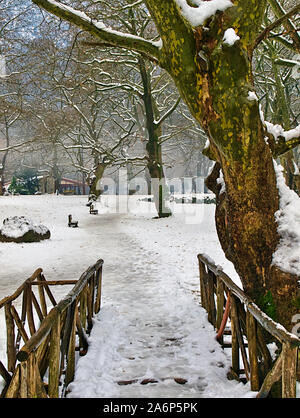 Eis überdachte Holzbrücke weg und Bänke im Schnee Agios Nikolaos (Sankt Nikolaus) Park in Syros Griechenland. Stockfoto