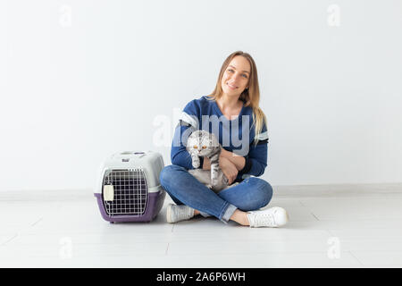 Charmante positive junge Frau hält in ihrer Hände ihre schönen grauen schottischen Katze sitzt auf dem Boden in eine neue Wohnung. Pet-Konzept. Stockfoto