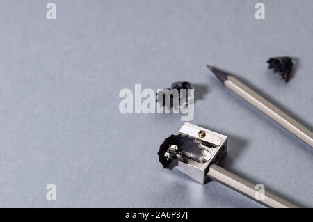 Zwei graue Bleistifte aus Holz, Metall Anspitzer und Späne auf grauem Hintergrund. Das Konzept des Minimalismus. Close Up. Stockfoto