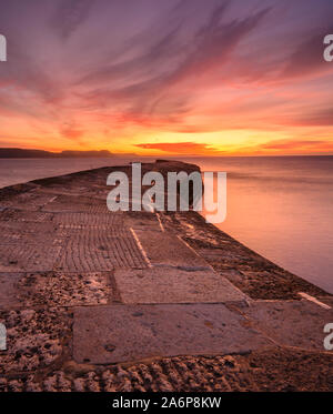 Lyme Regis, Dorset, Großbritannien. 28 Okt, 2019. UK Wetter: schönen Sonnenaufgang im Cobb Lyme Regis. Der Himmel über dem historischen Cobb Wand leuchtet mit brillanten Farben auf einem kühlen herbstlichen Morgen. Credit: Celia McMahon/Alamy leben Nachrichten Stockfoto