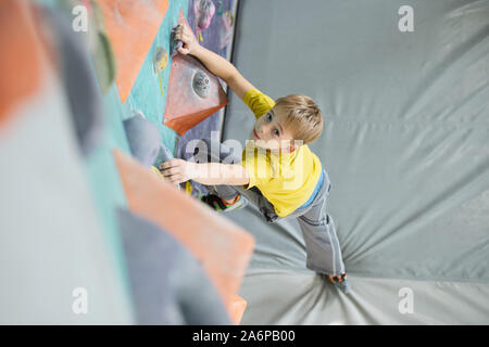 Schüler auf der Matte und halten einen Fuß auf Fels von Kletterausrüstung Stockfoto