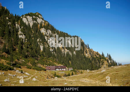 Malaesti challet im rumänischen Teil der Karpaten, mit Gipfeln hinter Tanne Wald im Herbst Farben und Stockfoto
