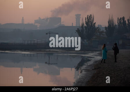 Mariupol, Ukraine. 24 Okt, 2019. Frauen nehmen Fotos am Ufer des Asowschen Meeres in Mariupol. Die zwei großen metallurgischen Anlagen in Mariupol basieren die Azovstal Eisen- und Stahlwerke und die iljitsch Eisen- und Stahlwerke Teil Метинвест Gruppe. Nach Angaben der ukrainischen Ökologie Bericht des Ministeriums im Jahr 2016 Iljitsch Anlage mehr als 1,7 Millionen Tonnen gefährlicher Emissionen in die Atmosphäre erzeugt und Asowschen Stal produziert 78.600 Tonnen atmosphärischer Schadstoffe und schüttete 1,4 Millionen Kubikmeter Abfall in das Asowsche Meer. Im Jahr 2018 des Ukrainischen Gesundheitsministeriums warnte die öffentlichkeit Schwimmen zu jeder o zu vermeiden. Stockfoto