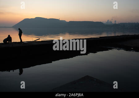 Mariupol, Ukraine. 24 Okt, 2019. Leute angeln an den Ufern des Asowschen Meer in Mariupol. Die zwei großen metallurgischen Anlagen in Mariupol basieren die Azovstal Eisen- und Stahlwerke und die iljitsch Eisen- und Stahlwerke Teil Метинвест Gruppe. Nach Angaben der ukrainischen Ökologie Bericht des Ministeriums im Jahr 2016 Iljitsch Anlage mehr als 1,7 Millionen Tonnen gefährlicher Emissionen in die Atmosphäre erzeugt und Asowschen Stal produziert 78.600 Tonnen atmosphärischer Schadstoffe und schüttete 1,4 Millionen Kubikmeter Abfall in das Asowsche Meer. Im Jahr 2018 der Ukraine Gesundheit Ministerium gewarnt, das öffentliche Schwimmbad in t zu vermeiden. Stockfoto