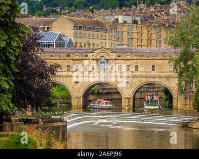 Pulteney Bridge mit Touristenkreuzfahrtschiffen unten gesehen, mit dem Pulteney Wehr im Vordergrund. Bad Somerset. Stockfoto