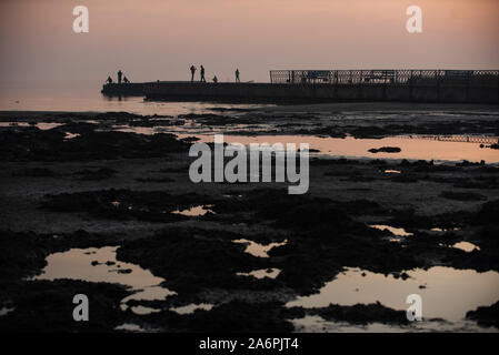 Mariupol, Ukraine. 24 Okt, 2019. Leute angeln an den Ufern des Asowschen Meer in Mariupol. Die zwei großen metallurgischen Anlagen in Mariupol basieren die Azovstal Eisen- und Stahlwerke und die iljitsch Eisen- und Stahlwerke Teil Метинвест Gruppe. Nach Angaben der ukrainischen Ökologie Bericht des Ministeriums im Jahr 2016 Iljitsch Anlage mehr als 1,7 Millionen Tonnen gefährlicher Emissionen in die Atmosphäre erzeugt und Asowschen Stal produziert 78.600 Tonnen atmosphärischer Schadstoffe und schüttete 1,4 Millionen Kubikmeter Abfall in das Asowsche Meer. Im Jahr 2018 der Ukraine Gesundheit Ministerium gewarnt, das öffentliche Schwimmbad in t zu vermeiden. Stockfoto