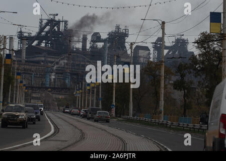 Mariupol, Ukraine. 25 Okt, 2019. Autos fahren durch eine Asowschen Stal Stahlwerk Avenue in Mariupol. Die zwei großen metallurgischen Anlagen in Mariupol basieren die Azovstal Eisen- und Stahlwerke und die iljitsch Eisen- und Stahlwerke Teil Метинвест Gruppe. Nach Angaben der ukrainischen Ökologie Bericht des Ministeriums im Jahr 2016 Iljitsch Anlage mehr als 1,7 Millionen Tonnen gefährlicher Emissionen in die Atmosphäre erzeugt und Asowschen Stal produziert 78.600 Tonnen atmosphärischer Schadstoffe und schüttete 1,4 Millionen Kubikmeter Abfall in das Asowsche Meer. Im Jahr 2018 des Ukrainischen Gesundheitsministeriums warnte die öffentlichen Schwimmbad jederzeit zu vermeiden. Stockfoto