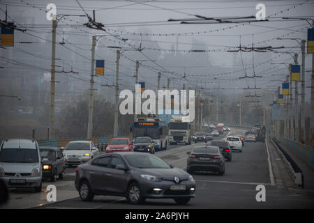 Mariupol, Ukraine. 25 Okt, 2019. Autos fahren durch eine Asowschen Stal Stahlwerk Avenue in Mariupol. Die zwei großen metallurgischen Anlagen in Mariupol basieren die Azovstal Eisen- und Stahlwerke und die iljitsch Eisen- und Stahlwerke Teil Метинвест Gruppe. Nach Angaben der ukrainischen Ökologie Bericht des Ministeriums im Jahr 2016 Iljitsch Anlage mehr als 1,7 Millionen Tonnen gefährlicher Emissionen in die Atmosphäre erzeugt und Asowschen Stal produziert 78.600 Tonnen atmosphärischer Schadstoffe und schüttete 1,4 Millionen Kubikmeter Abfall in das Asowsche Meer. Im Jahr 2018 des Ukrainischen Gesundheitsministeriums warnte die öffentlichen Schwimmbad jederzeit zu vermeiden. Stockfoto