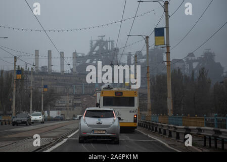 Mariupol, Ukraine. 25 Okt, 2019. Autos fahren durch eine Asowschen Stal Stahlwerk Avenue in Mariupol. Die zwei großen metallurgischen Anlagen in Mariupol basieren die Azovstal Eisen- und Stahlwerke und die iljitsch Eisen- und Stahlwerke Teil Метинвест Gruppe. Nach Angaben der ukrainischen Ökologie Bericht des Ministeriums im Jahr 2016 Iljitsch Anlage mehr als 1,7 Millionen Tonnen gefährlicher Emissionen in die Atmosphäre erzeugt und Asowschen Stal produziert 78.600 Tonnen atmosphärischer Schadstoffe und schüttete 1,4 Millionen Kubikmeter Abfall in das Asowsche Meer. Im Jahr 2018 des Ukrainischen Gesundheitsministeriums warnte die öffentlichen Schwimmbad jederzeit zu vermeiden. Stockfoto