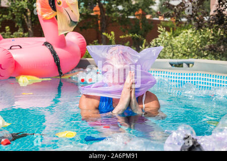 Ökologie, Kunststoff Papierkorb, Umwelt- und Wasserverschmutzung - verzweifelte Hoffnung Mann mit einer Plastiktüte über den Kopf in einem dreckigen Pool Stockfoto