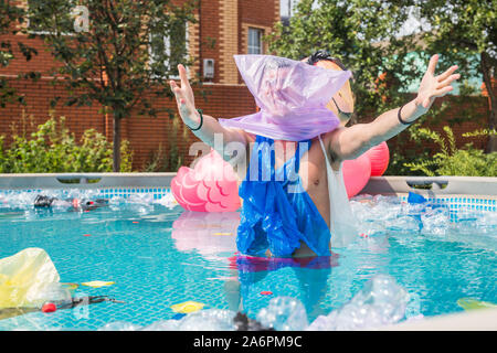 Ökologie, Kunststoff Papierkorb, Umwelt- und Wasserverschmutzung - Schreiende Mann mit einer Plastiktüte über den Kopf in einem dreckigen Pool Stockfoto