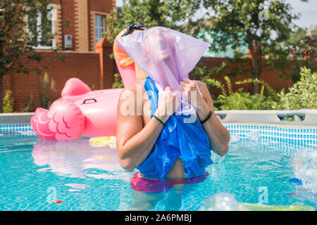 Ökologie, Kunststoff Papierkorb, Umwelt- und Wasserverschmutzung - Schreiende Mann mit einer Plastiktüte über den Kopf in einem dreckigen Pool Stockfoto