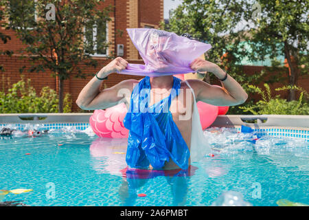 Ökologie, Kunststoff Papierkorb, Umwelt- und Wasserverschmutzung - Schreiende Mann mit einer Plastiktüte über den Kopf in einem dreckigen Pool Stockfoto