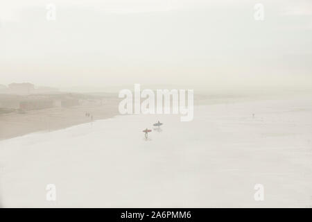 Surfer in den frühen Morgenstunden Nebel bei einem langen Strand von Muizenberg an der False Bay, Kapstadt, Südafrika Stockfoto