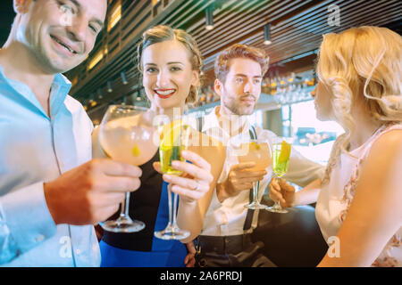 Freunde zur Bar und Trinken von zuckerhaltigen alkoholischen Getränken Stockfoto