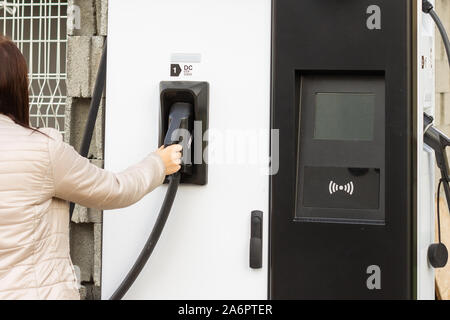 Frau verwenden elektrische Fast Charger mit Elektro- oder Hybridautos. High-tech Ladegerät für grüne Fahrweise PHEV. Ökologie freundlich Ladegerät Stockfoto