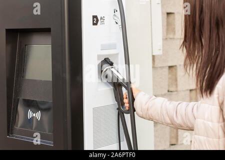 Frau verwenden elektrische Fast Charger mit Elektro- oder Hybridautos. High-tech Ladegerät für grüne Fahrweise PHEV. Ökologie freundlich Ladegerät Stockfoto