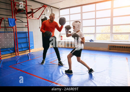 Wütend ernste Zicklein auf Boxen mit Jungen hndsome Mann konzentriert, volle Länge Foto. Motivation, Wellness, Junge hält fit Stockfoto